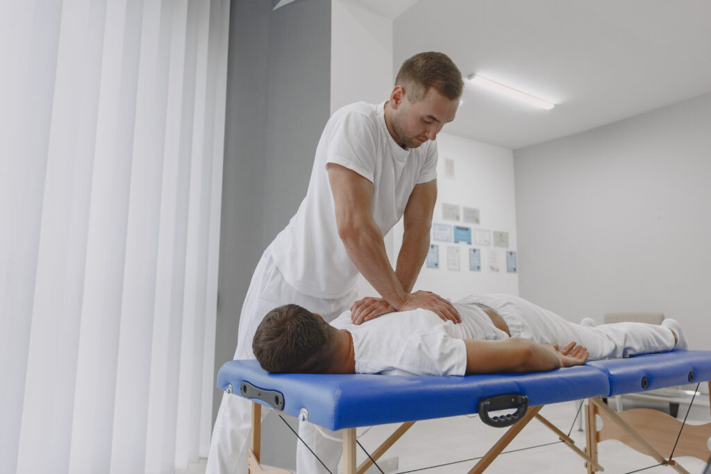Man in the medical office offering services. Physiotherapist is rehabilitating back.